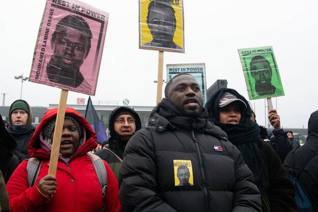 Menschen protestieren mit Plakaten auf den das Gesicht des durch Polizeischüsse gtöteten Mouhamed Dramé zu sehen ist