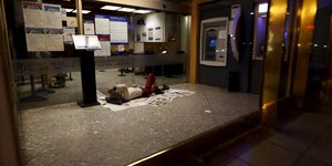 Ein Mann liegt auf dem Boden im Vorraum einer Bank und schläft