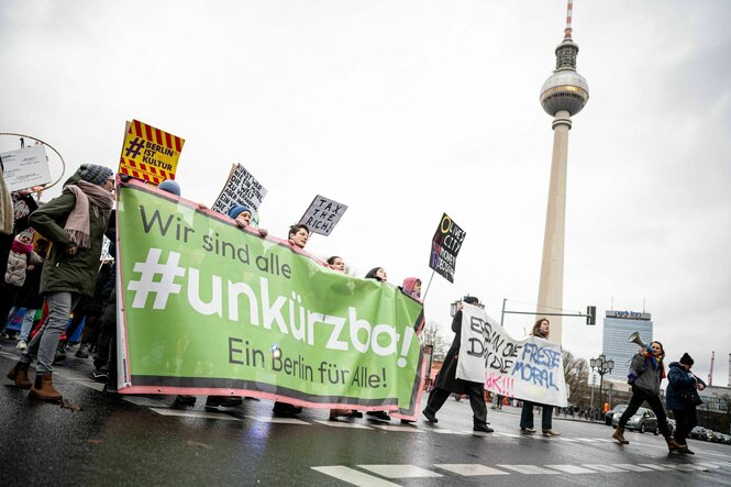 Teilnehmer laufen auf der Demonstration des Bündnisses «#Unkürzbar!» gegen Sparpläne des Berliner Senats vor dem Fernsehturm durch Berlin-Mitte mit einem Banner mit der Aufschrift ?Wir sind alle unkürzbar