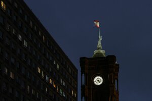 Das Rote Rathaus bei Nacht: Ein Uhrturm auf dem die Berliner Fahne mit dem Bären weht.