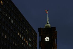 Das Rote Rathaus bei Nacht: Ein Uhrturm auf dem die Berliner Fahne mit dem Bären weht.