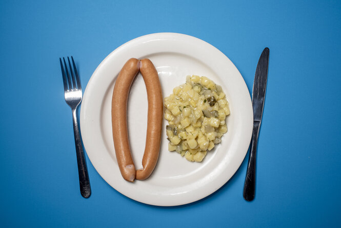 Ein Teller mit Kartoffelsalat und Würstchen.