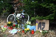 Ein weißes Fahrrad und Blumen liegen zum Gedenken am Unfallort