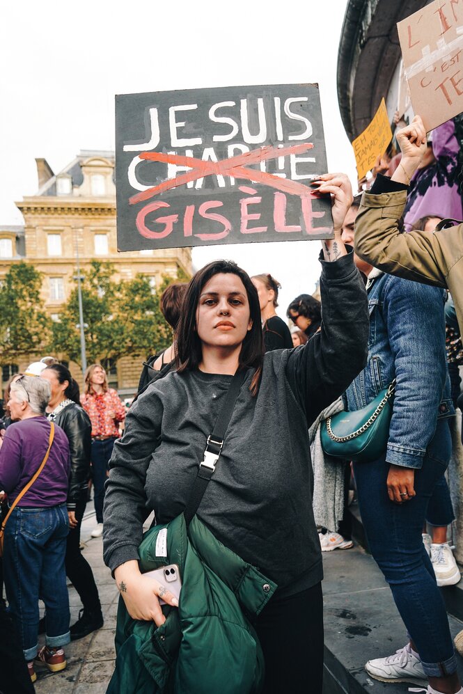 Eine Frau hält ein Schild in die Höhe, darauf ist zu lesen "Je suis Gisèle"