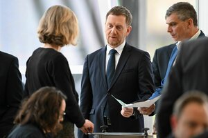 Michael Kretschmer steht an einer Wahlurne und hält einen Stimmzettel in den Händen