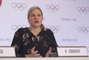 Foto von Kirsty Coventry auf dem Podium einer Pressekonferenz mit den olympischen Ringen im Hintergrund