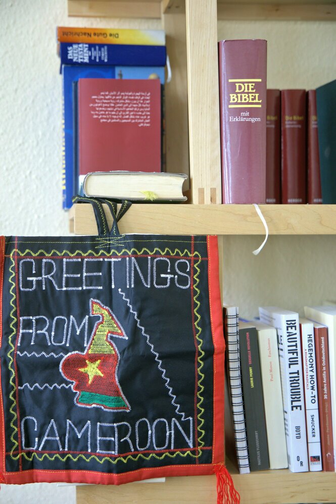 Besticktes Bild "Greetings from Cameroon" im Bücherregal