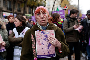 Eine Frau hält eine Plakat mit dem Konterfei von Gisel pelicot und dem Wort 