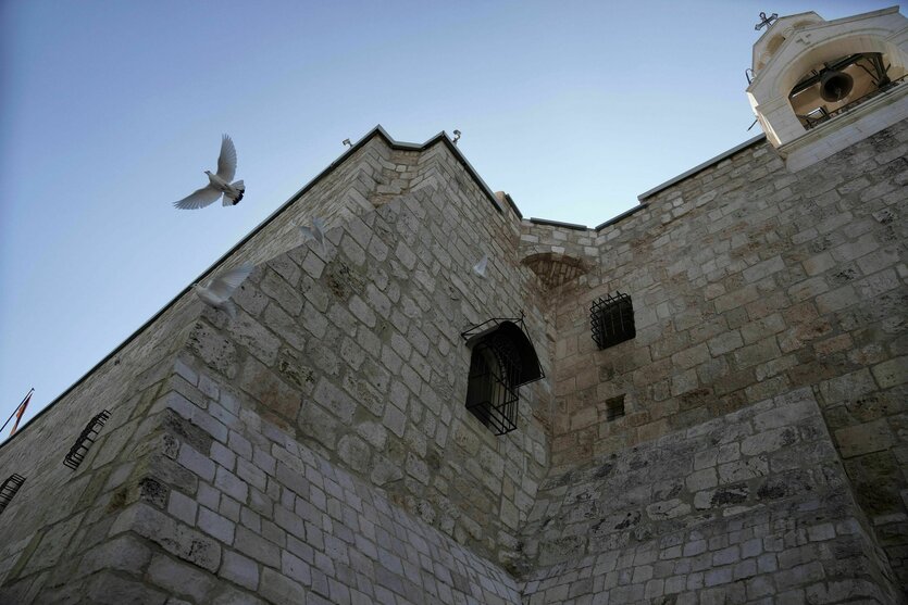 Eine Taube fliegt vor dem Gemäuer einer Kirche