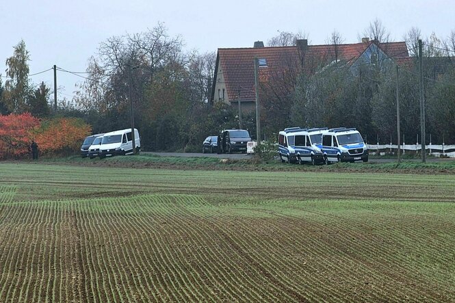 Einsatzfahrzeuge der Polizei stehen am Rand eines Feldes