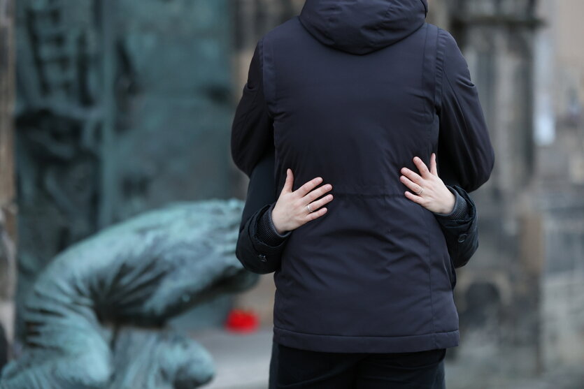 Sich umarmende Menschen vor einem Denkmal