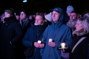 Menschen in Regenjacken halten Kerzen in der Hand