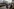 Im Vordergrund sitzt ein Pärchen an einem Tisch vor einem Restaurant. Auf der gegenüberliegenden Straßenseite das palastartige Gebäude der katarischen Botschaft. Er macht ein Handyfoto des Gebäudes.