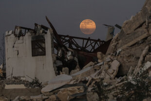 Der Vollmond geht am frühen Abend über zerstörten Gebäuden im Zentrum des Gazastreifens auf