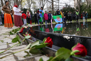 Menschen mit einer Fahne und Rosen an einem Wasserbeckeen