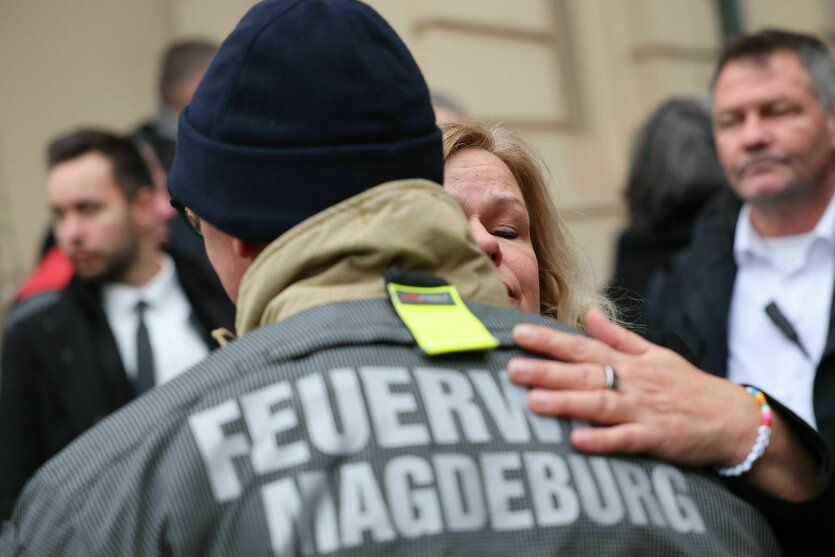 Faeser legt einem Feuerwehrmann den Arm auf die Schulter