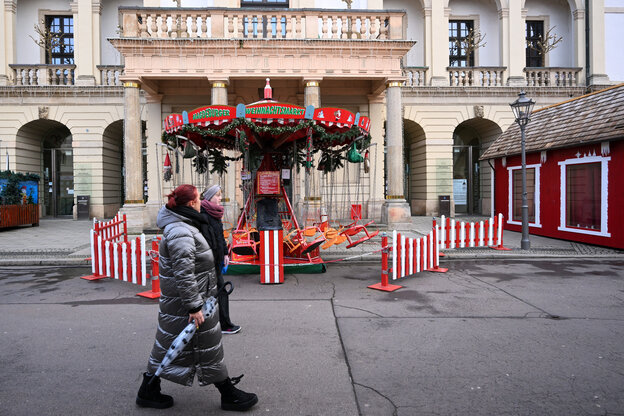 PassantInnen gehen an einem verlassenenen Kinderkarussell am Alten Markt in Magdeburg vorbei