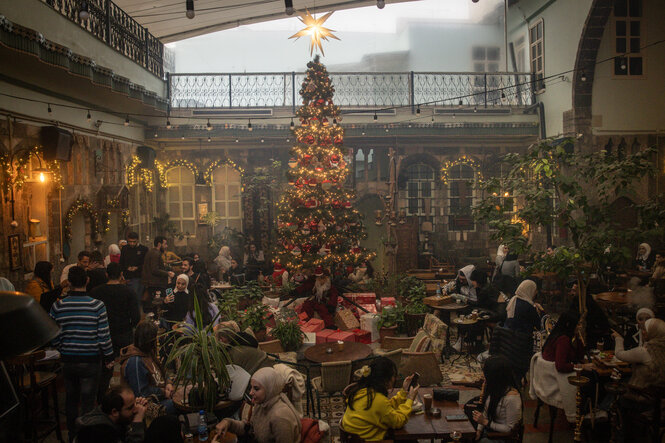 Blick in einen hohen Raum mit großem Weihnachtsbaum und vielen Menschen