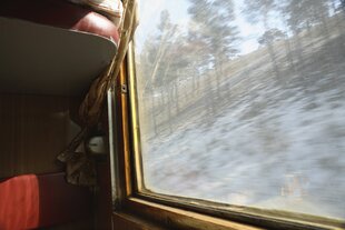 Blick aus einem Zugfenster, draußen liegt etwas Schnee