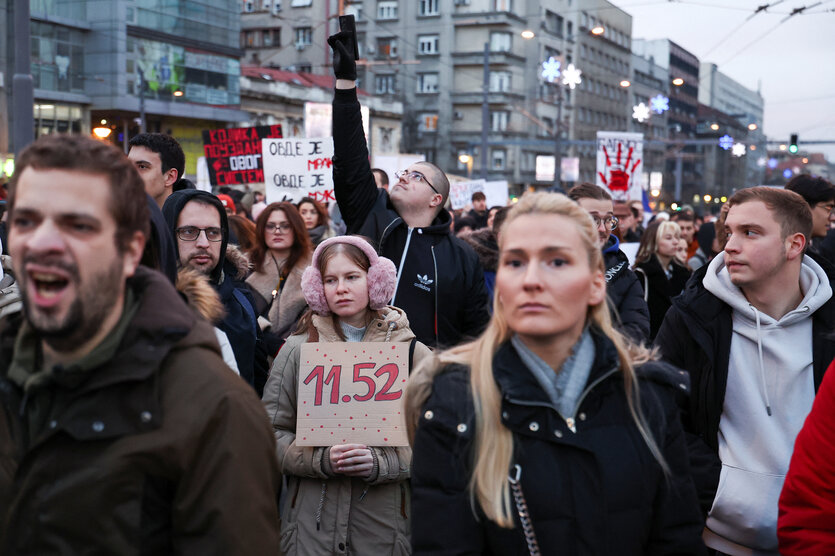 DemonstranTinnen in Belgrad: eine Junge Frau mit einem Schild 11:52, dem Zeitpunkt der Katastrophe