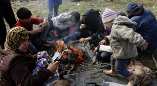 Menschen sitzen um ein kleines Feuer