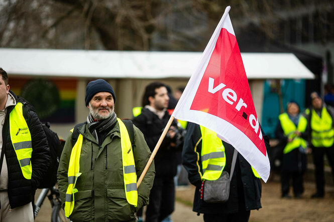 Ein Demonstrierender mit Verdi Fahne. Kundgebung während dem Streik der BVG und dem Klimastreiktag am 1. März 2024