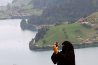 Vollverschleierte Frau macht ein Foto vor Schweizer Idylle