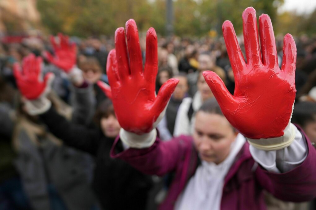 Menschen halten ihre rot bemalten Hände als Protest in die Höhe