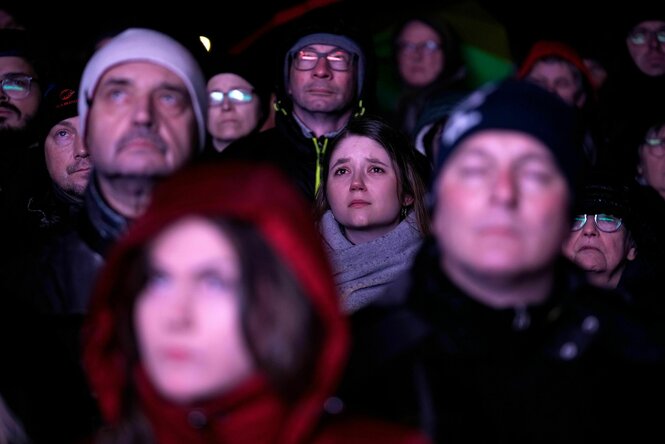 Eine Gruppe von Menschen stehen in der dunkelheit beieinander und blicken ernst