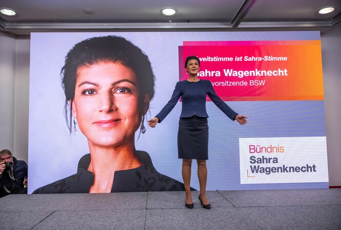 Sahra Wagenknecht steht vor einem Plakat mit ihrem Konterfei