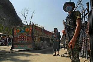 Ein pakistanischer Soldat (r) und Kämpfer der Taliban stehen Wache an einem Grenzübergang zwischen Pakistan und Afghanistan