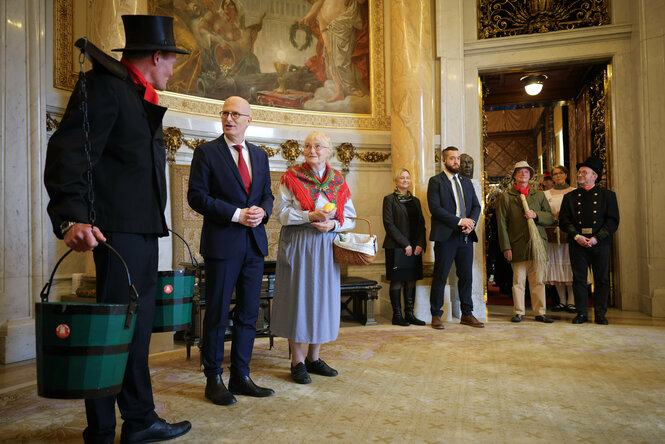 Ein Wasserträger steht nebem Bürgermeister Peter Tschentscher im Rathaus