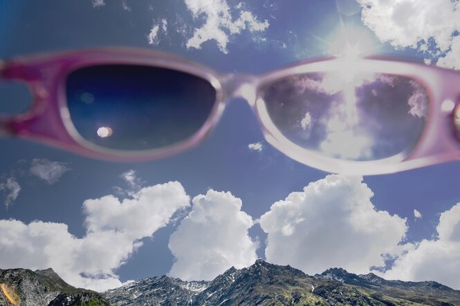 Eine rosarote Sonnenbrille vor Alpenkulisse