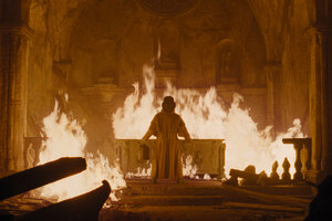 Einer der Protagonisten des Films, Professor Albin Eberhart von Franz, steht in einem kirchenartigen Raum vor einem brennenden Altar, Szene aus dem Film.