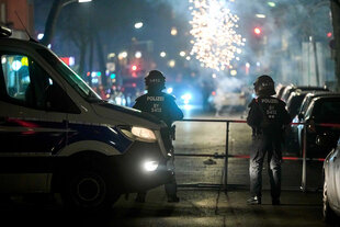 Polizisten an einer Absperrung schauen sich ein Feuerwerk an