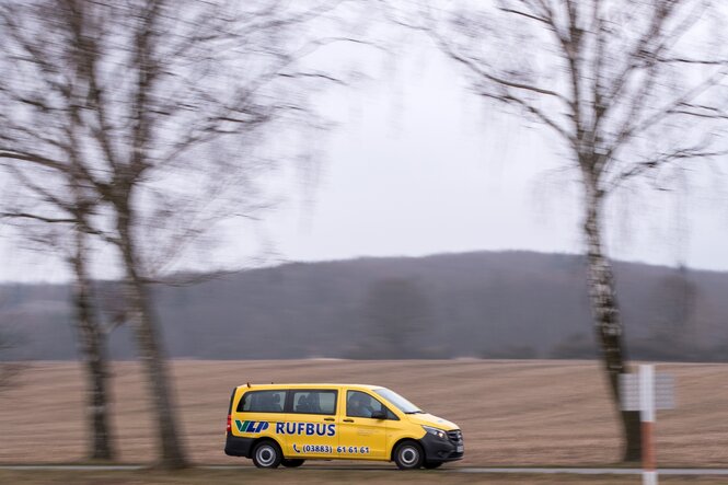 ein gelber kleiner Rufbus fährt durch eine Winterlandschaft