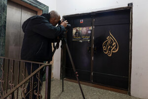 Ein Mann fotografiert das mit einem Logo verzierte Büro des Senders Al Jazeera in Ramallah