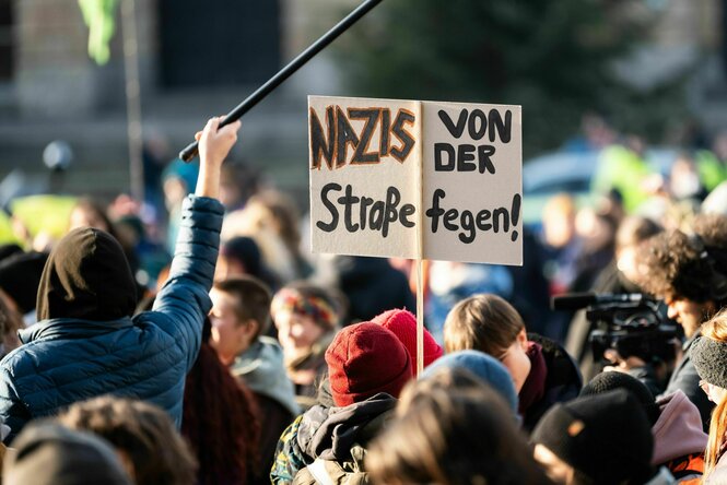 Ein Demonstrant hält während einer Versammlung gegen Rechts auf dem Platz der Alten Synagoge in Freiburg ein Schild in die Höhe.