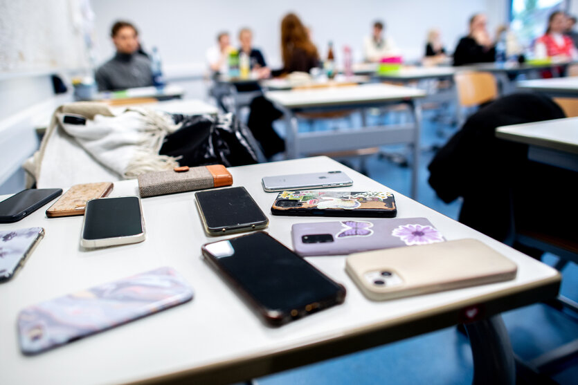 Handys liegen in einem Klassenzimmer auf einemTisch