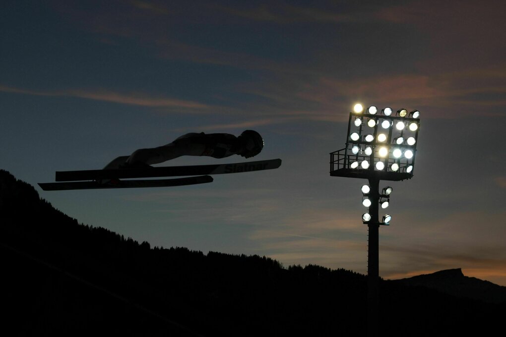 Nachtaufnahme Skispringerin als Silhouette im Flutlicht