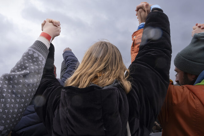 Menschen halten stehen in einer Menge zusammen, halten sich an den Händen und strecken diese in die Höhe