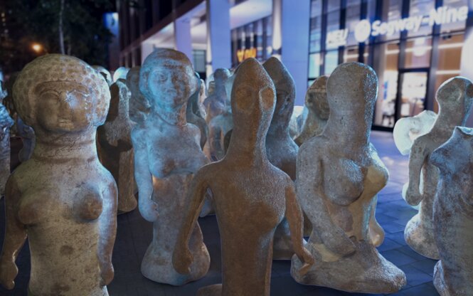 Animierte Terrakottafiguren von Frauen protestieren auf einer Straße.