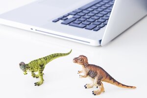 2 Plastik-Dinosaurier neben einem Laptop