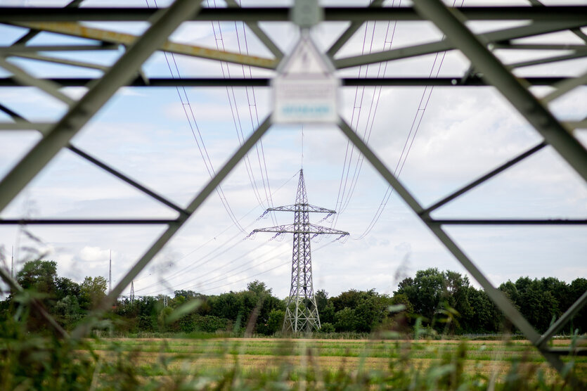 Eine Hochspannungsleitung führt über ein Feld am Ortsrand