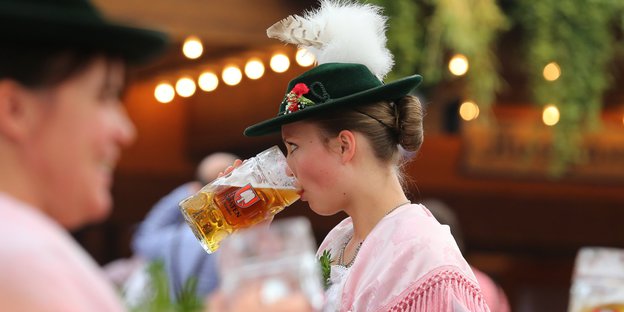 Eine Frau in Tracht trinkt Bier