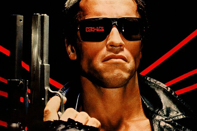 Arnold Schwarzenegger als Terminator hält eine Waffe in der Hand und trägt eine schwarze Sonnenbrille