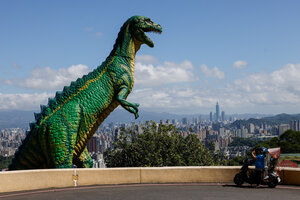 Eine Frau auf einem Roller macht ein Foto einer Dinosaurier-Statue in Taiwan.