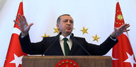 Erdogan auf einem Podium vor türkischen Fahnen
