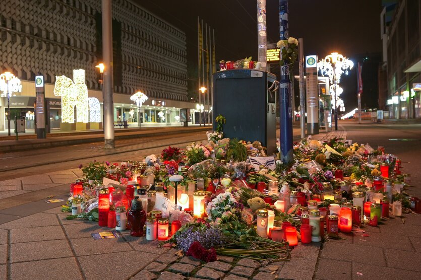 Blumen und Kerzen stehen im Gedenken an die Anschlagsopfer in Magdeburg an einer Straßenbahnhaltestelle