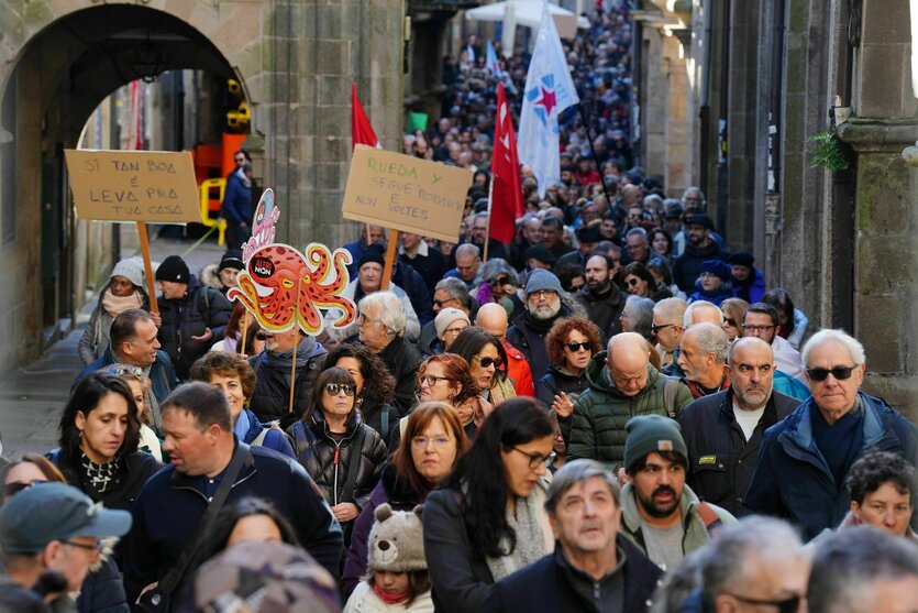 Menschen gehen mit Protestschildern durch die engen Gassen einer Altstadt